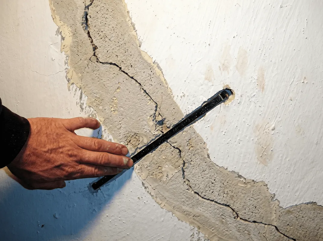A wall with a large crack is being inspected by a professional in Dayton, OH